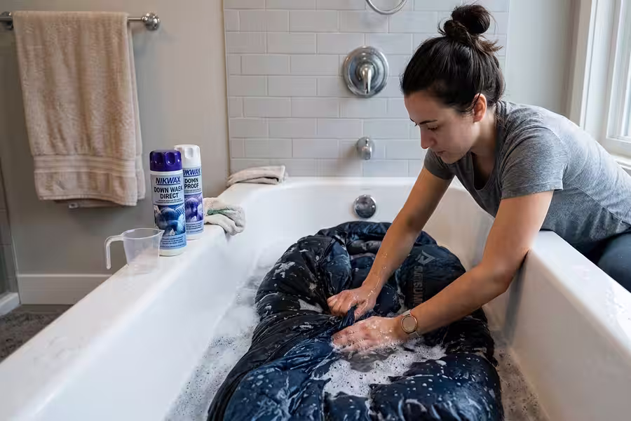 Hand washing a down sleeping bag in a bathtub with specialized detergent